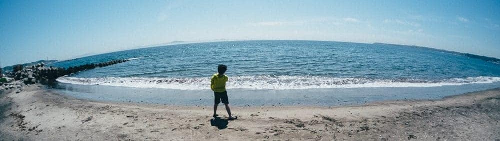 Wide angle shot of a boy walking along a beach.